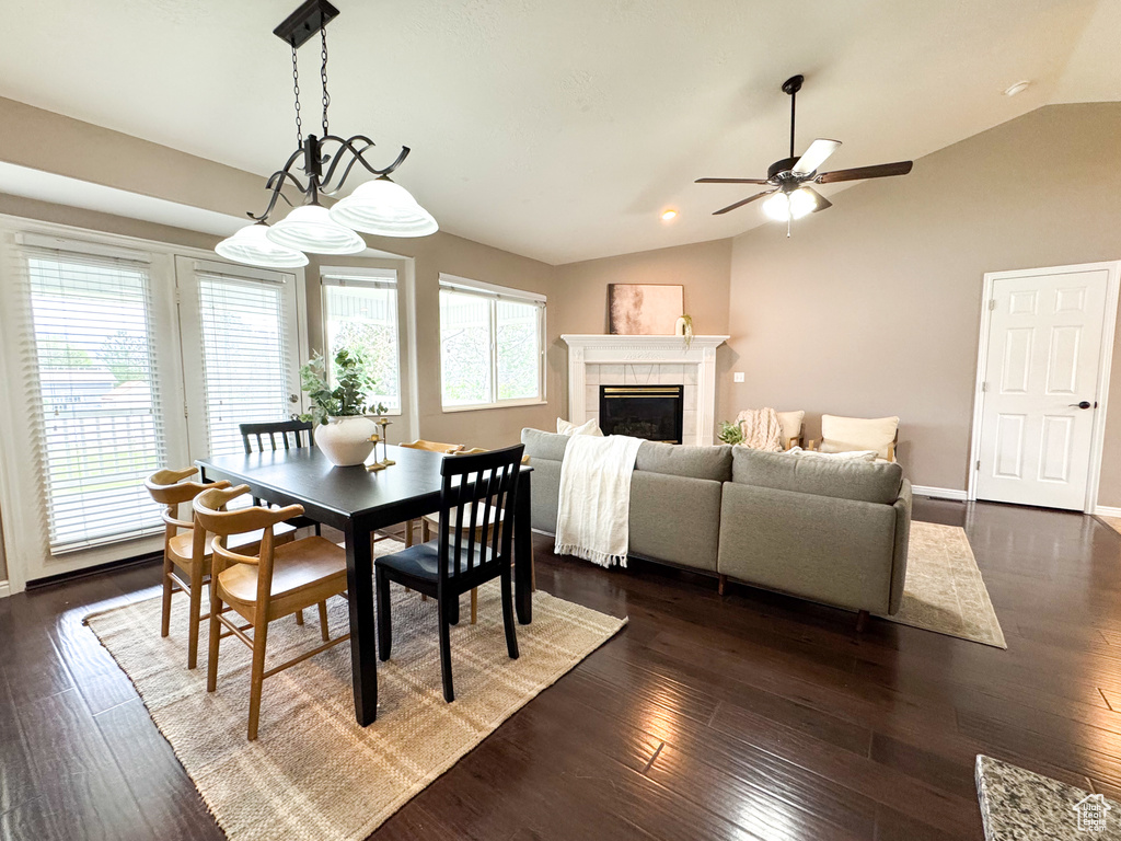 Dining area featuring vaulted ceiling, ceiling fan, a fireplace, dark wood-type flooring, and baseboards