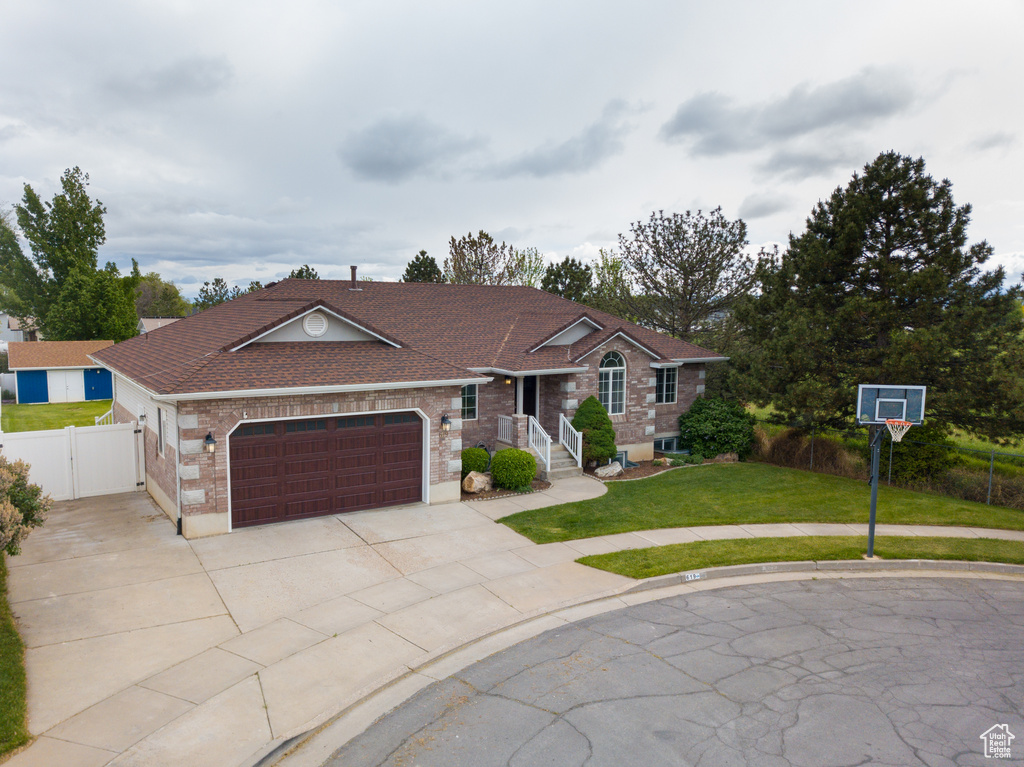 Ranch-style home featuring brick siding, an attached garage, a gate, a shingled roof, and concrete driveway