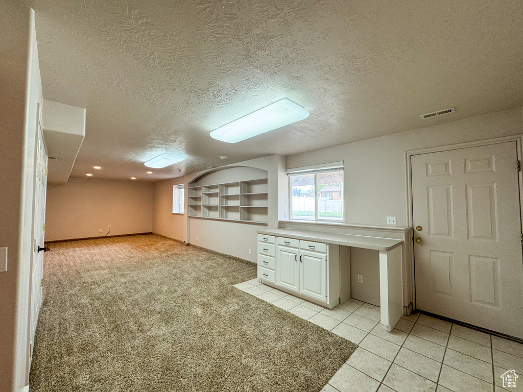 Bonus room with a textured ceiling, light tile patterned floors, light carpet, and recessed lighting