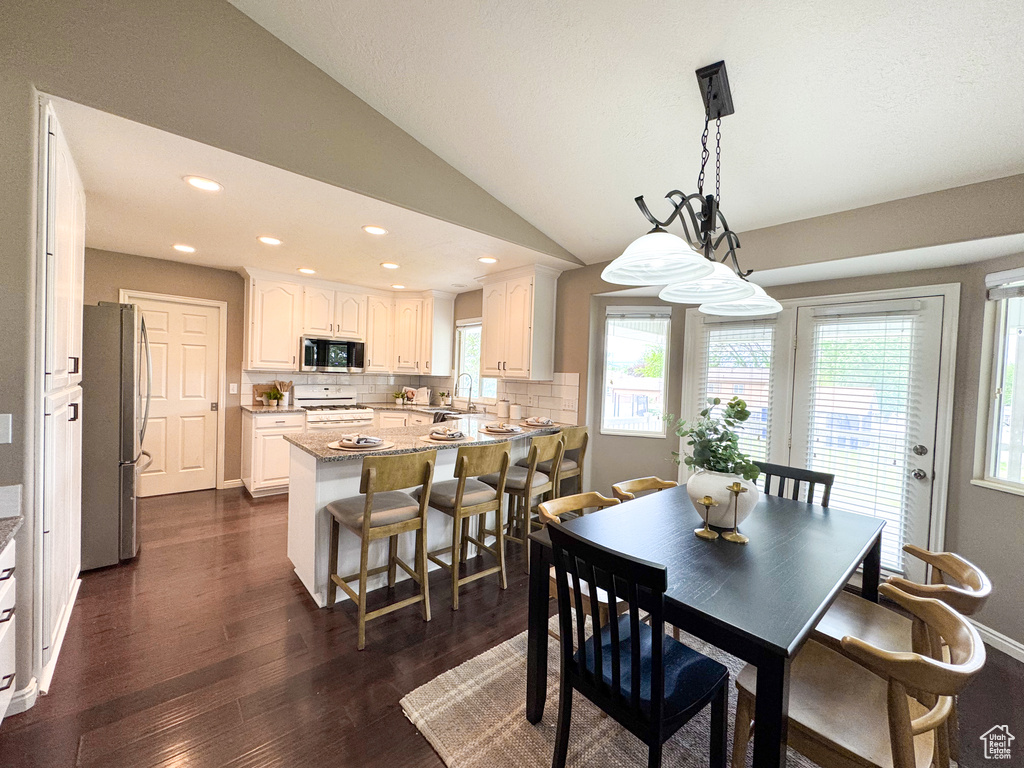 Dining room with dark wood finished floors, recessed lighting, and lofted ceiling