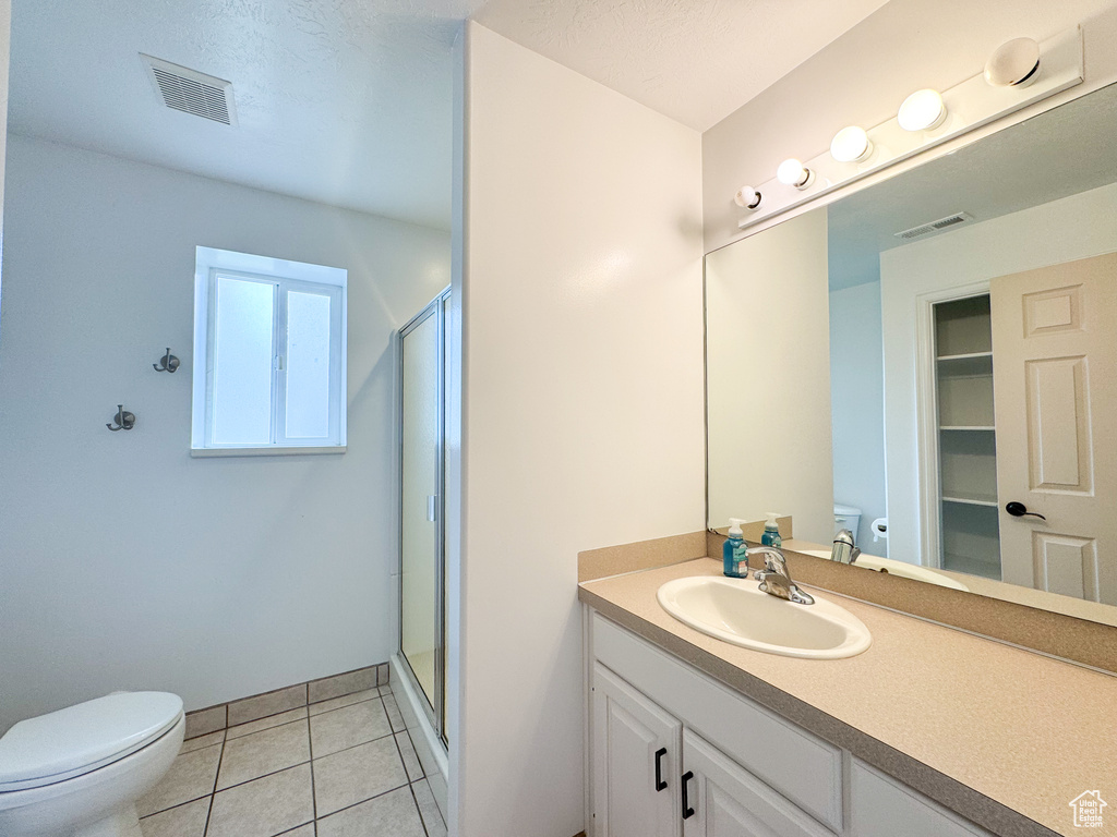Full bathroom featuring toilet, a stall shower, vanity, and tile patterned flooring