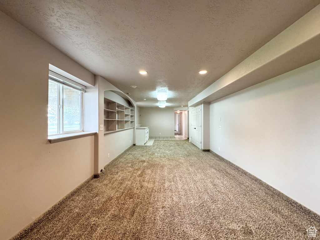 Below grade area featuring light carpet, a textured ceiling, and recessed lighting