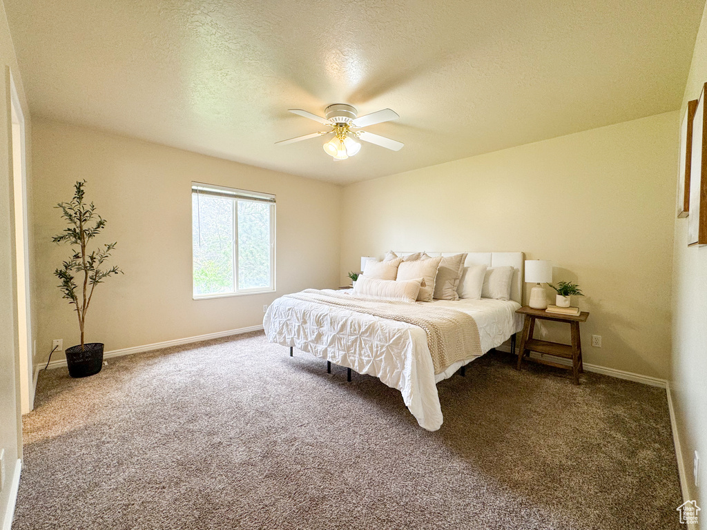 Bedroom with carpet flooring, baseboards, a ceiling fan, and a textured ceiling