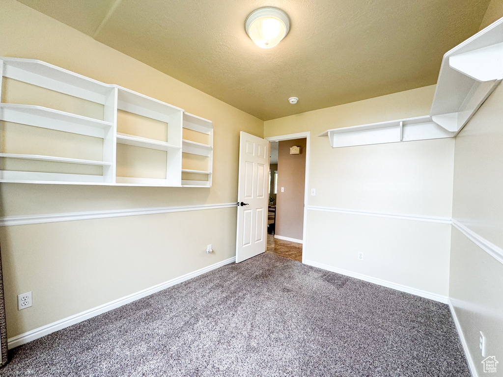 Carpeted spare room featuring baseboards and a textured ceiling