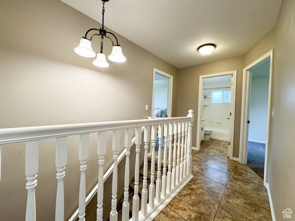 Corridor featuring a chandelier, an upstairs landing, tile patterned flooring, and baseboards