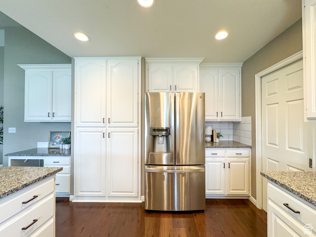 Kitchen with stainless steel fridge with ice dispenser, dark wood finished floors, light stone counters, white cabinetry, and recessed lighting