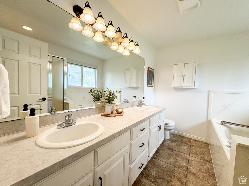 Full bath featuring a garden tub, double vanity, toilet, and baseboards