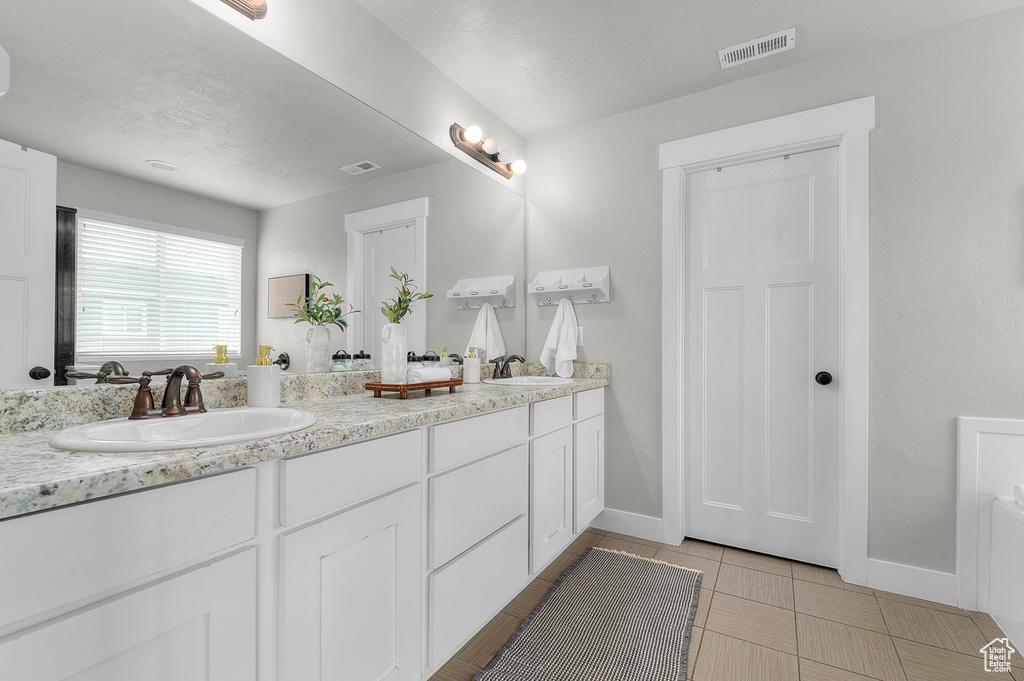 Full bath featuring baseboards and double vanity
