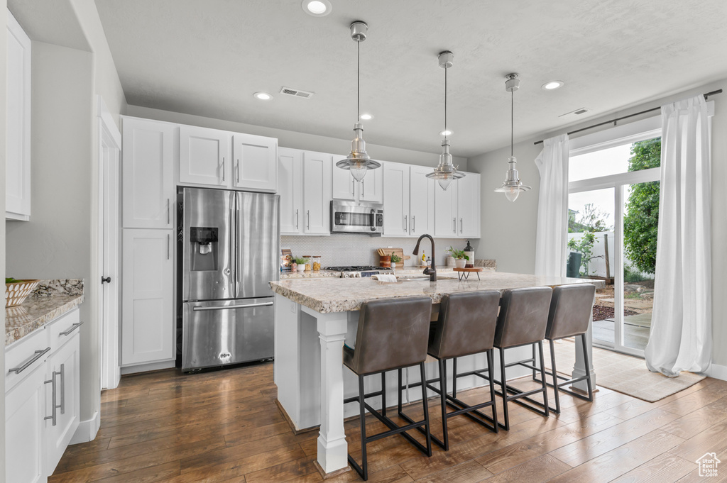 Kitchen with stainless steel appliances, dark wood-type flooring, recessed lighting, and light stone counters