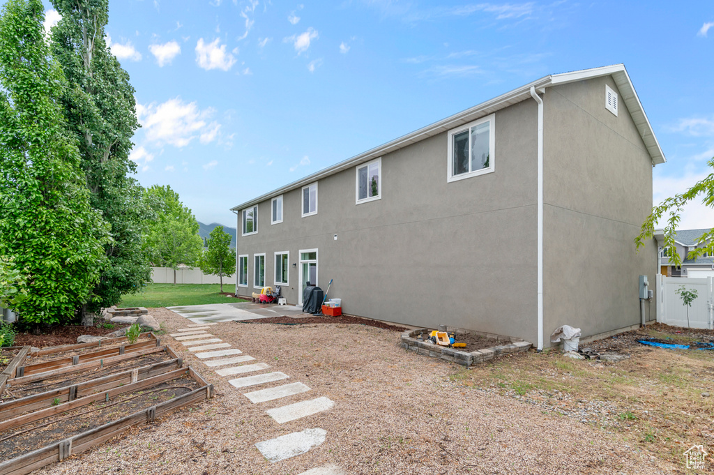 Rear view of property featuring fence, stucco siding, and a patio