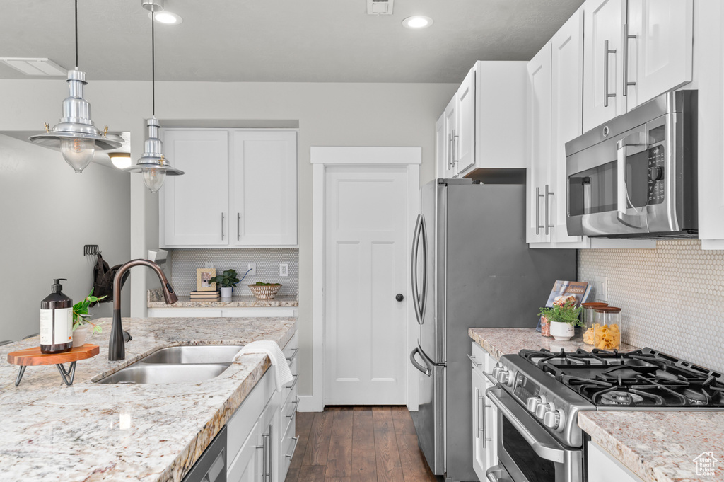 Kitchen with stainless steel appliances, a sink, white cabinets, decorative backsplash, and recessed lighting