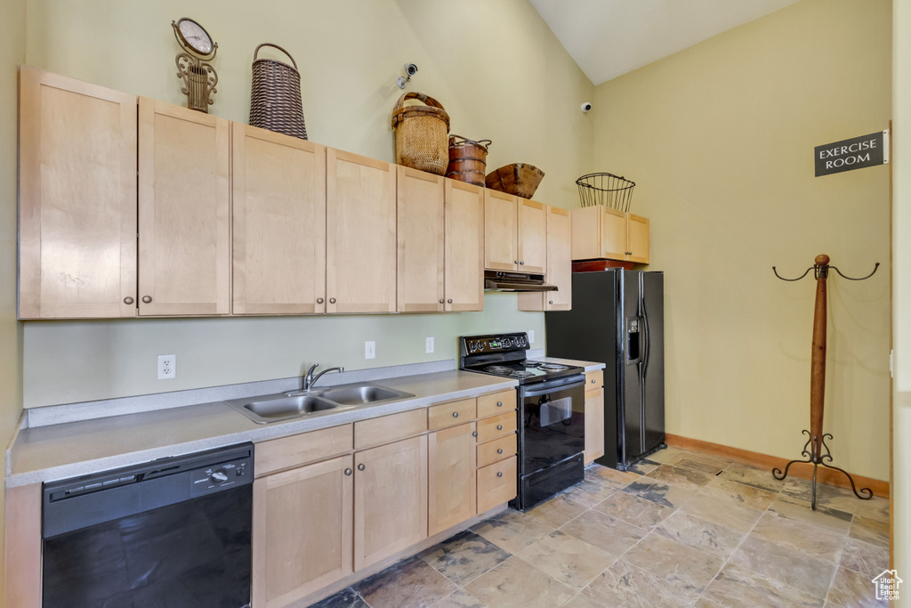 Kitchen featuring black appliances, light brown cabinets, a sink, under cabinet range hood, and light stone finish flooring
