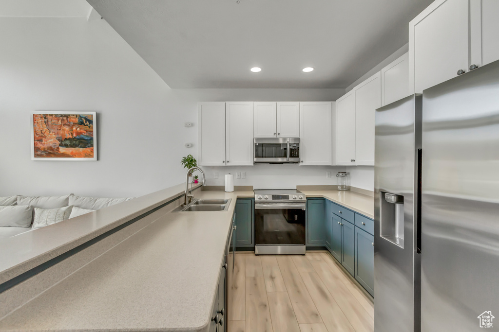 Kitchen featuring appliances with stainless steel finishes, recessed lighting, white cabinetry, light wood-style flooring, and light countertops