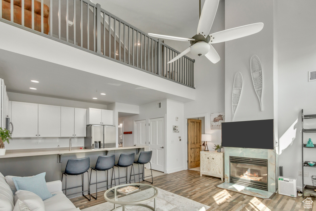 Living room featuring a towering ceiling, light wood-style floors, recessed lighting, and a ceiling fan