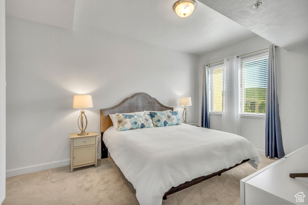 Bedroom with light colored carpet and baseboards