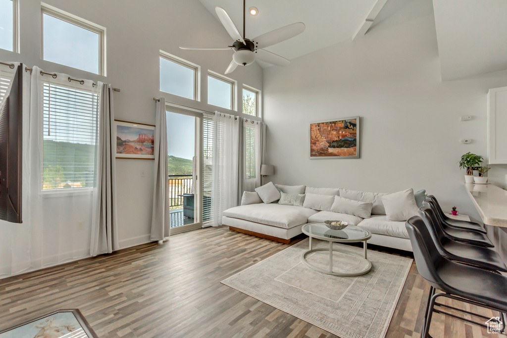 Living area with a ceiling fan, light wood-style floors, high vaulted ceiling, and baseboards