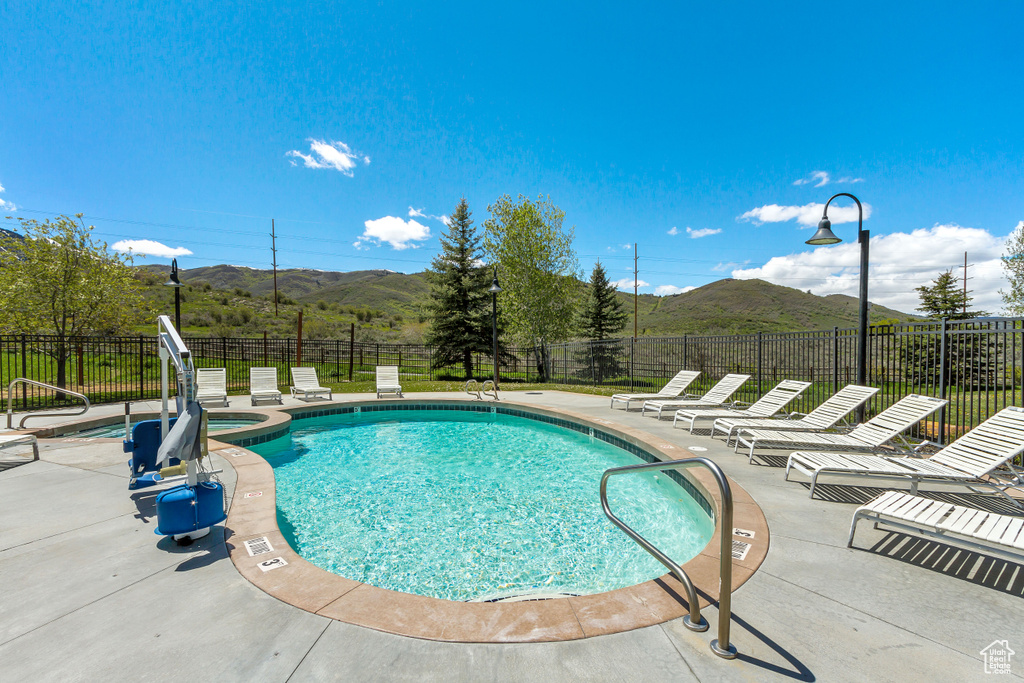 View of pool with a mountain view, a patio, and a pool with connected hot tub