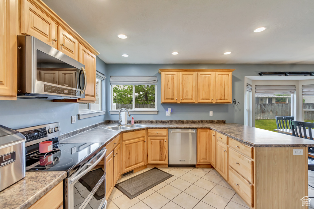 Kitchen with appliances with stainless steel finishes, a sink, light brown cabinetry, a peninsula, and recessed lighting