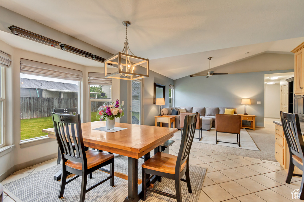 Dining room with a chandelier, light tile patterned floors, vaulted ceiling, and ceiling fan
