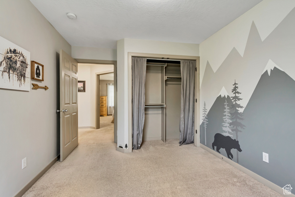 Bedroom with light carpet, a closet, and baseboards