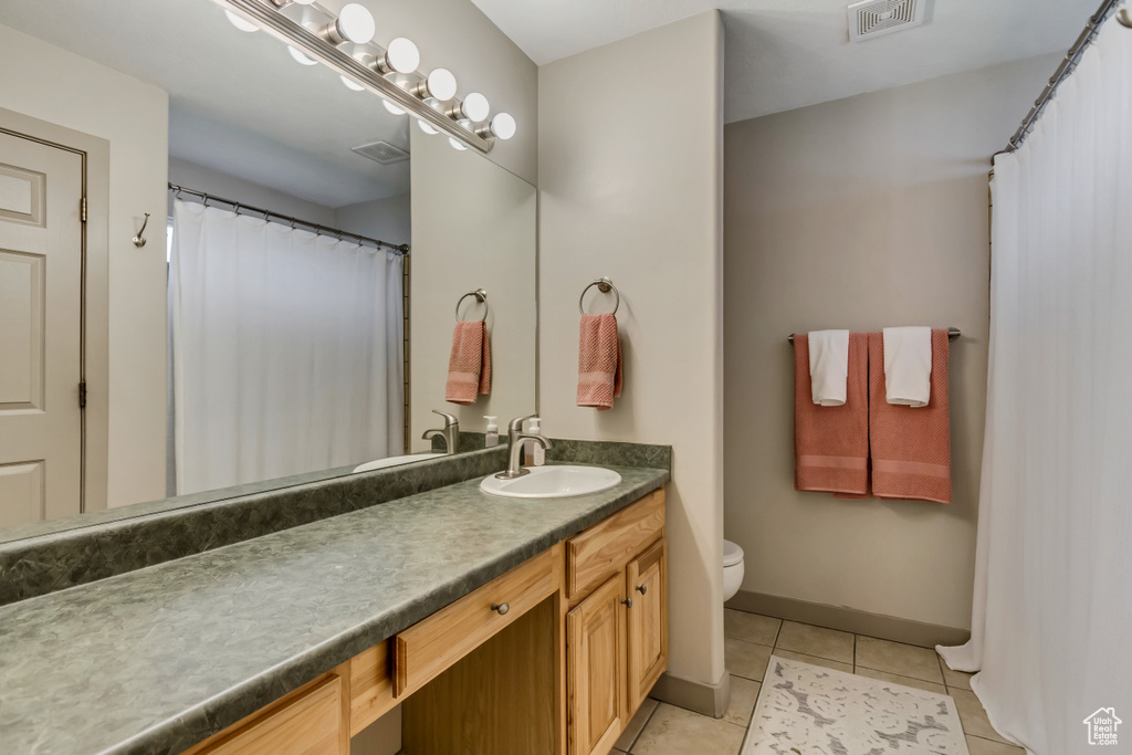 Bathroom featuring vanity, tile patterned floors, toilet, and baseboards