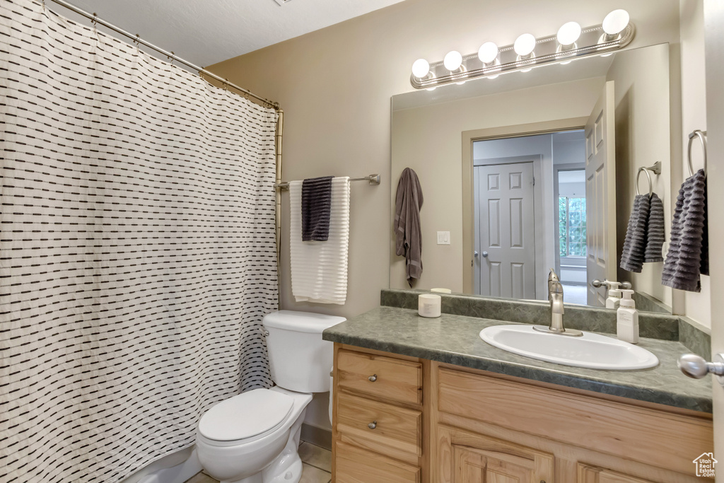 Bathroom featuring toilet, vanity, and a shower with shower curtain