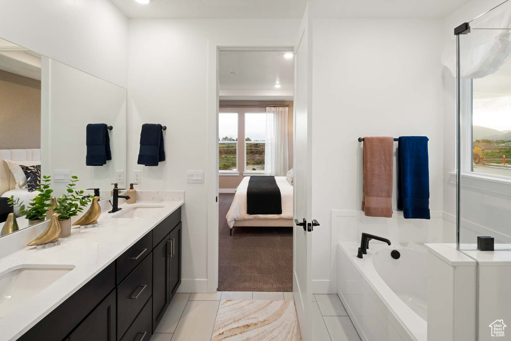 Bathroom with ensuite bathroom, double vanity, a bath, tile patterned flooring, and baseboards