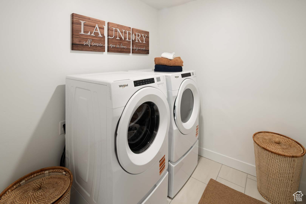Washroom with washer and clothes dryer and light tile patterned flooring