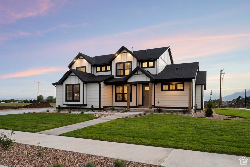 Modern farmhouse style home with board and batten siding, a front yard, a porch, and roof with shingles