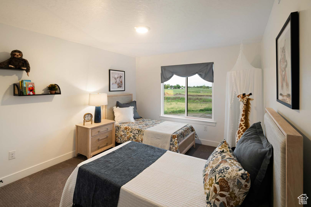 Bedroom with dark colored carpet and baseboards