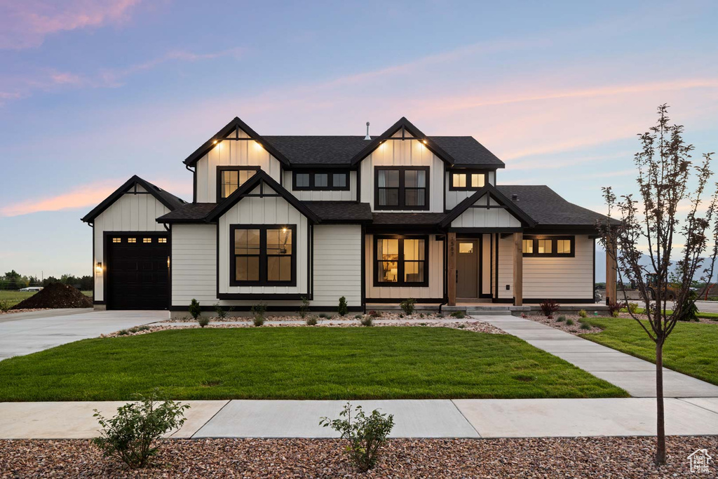 Modern farmhouse featuring concrete driveway, board and batten siding, a front yard, and a shingled roof