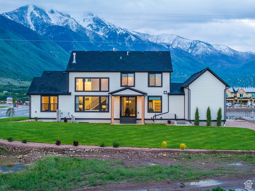 Rear view of house with a mountain view and a lawn