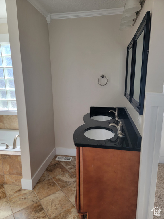Bathroom with crown molding, baseboards, a bath, and double vanity