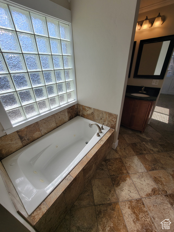Bathroom with stone tile floors, a tub with jets, and vanity