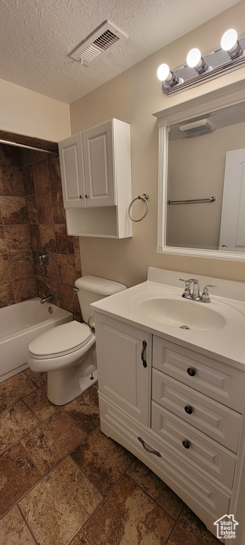 Bathroom featuring toilet, vanity, a textured ceiling, and shower / bath combination