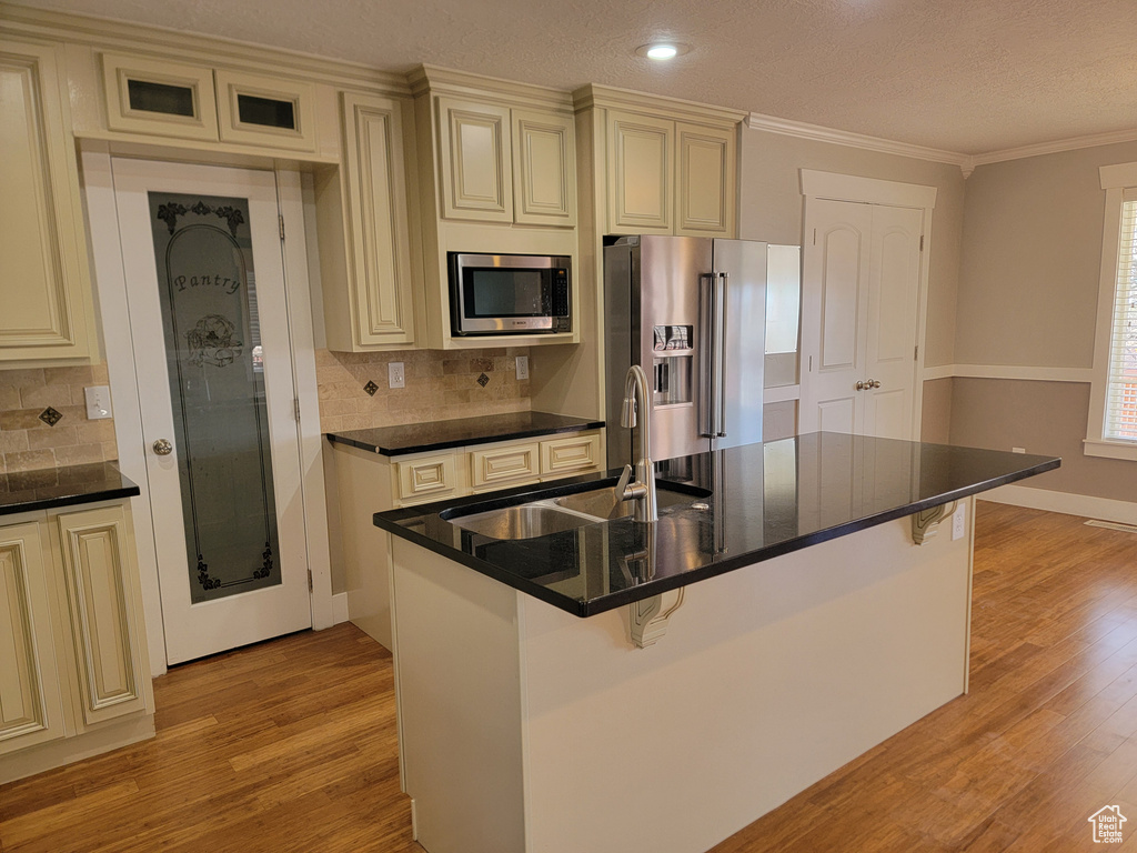 Kitchen with cream cabinets, appliances with stainless steel finishes, crown molding, a textured ceiling, and recessed lighting