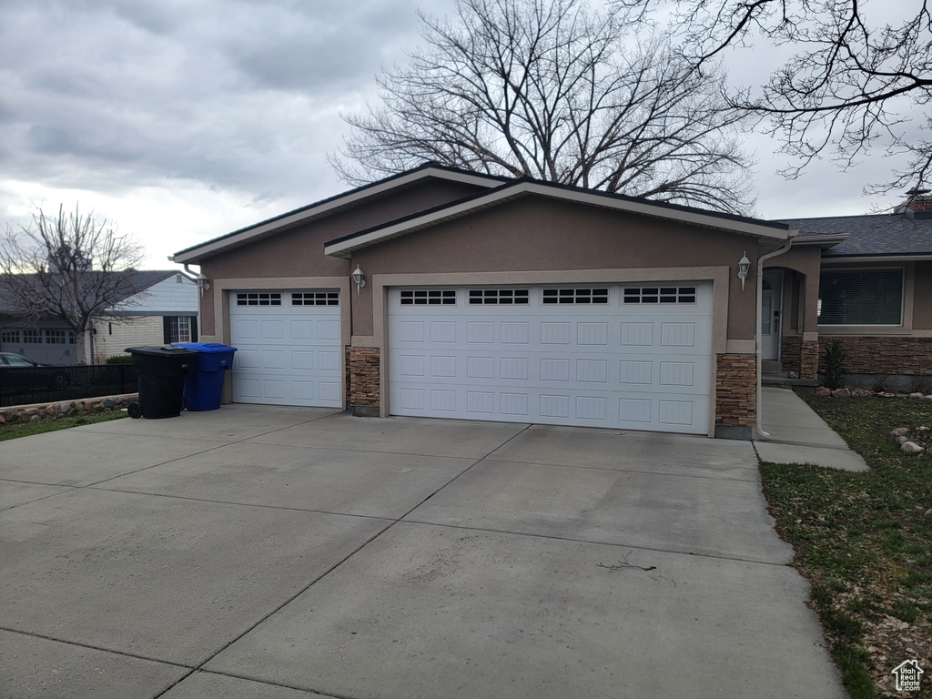 Ranch-style house featuring stone siding, an attached garage, and concrete driveway