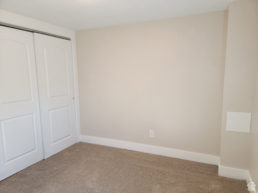 Unfurnished bedroom with carpet, a closet, and baseboards