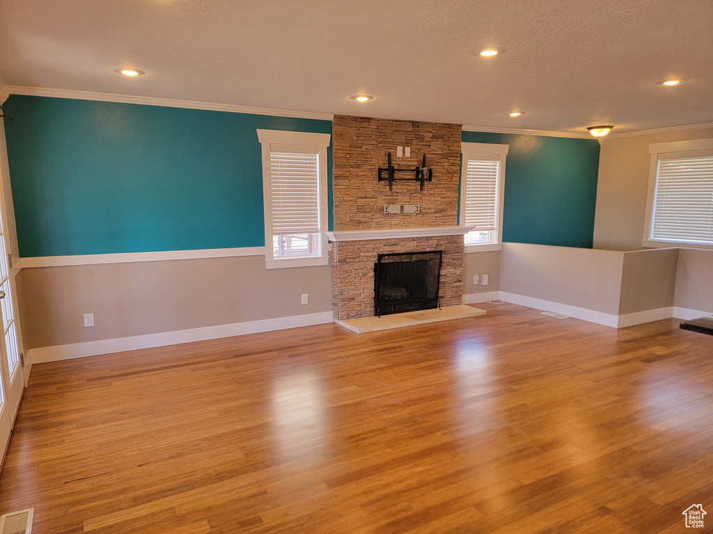 Unfurnished living room with ornamental molding, a fireplace, baseboards, wood finished floors, and recessed lighting