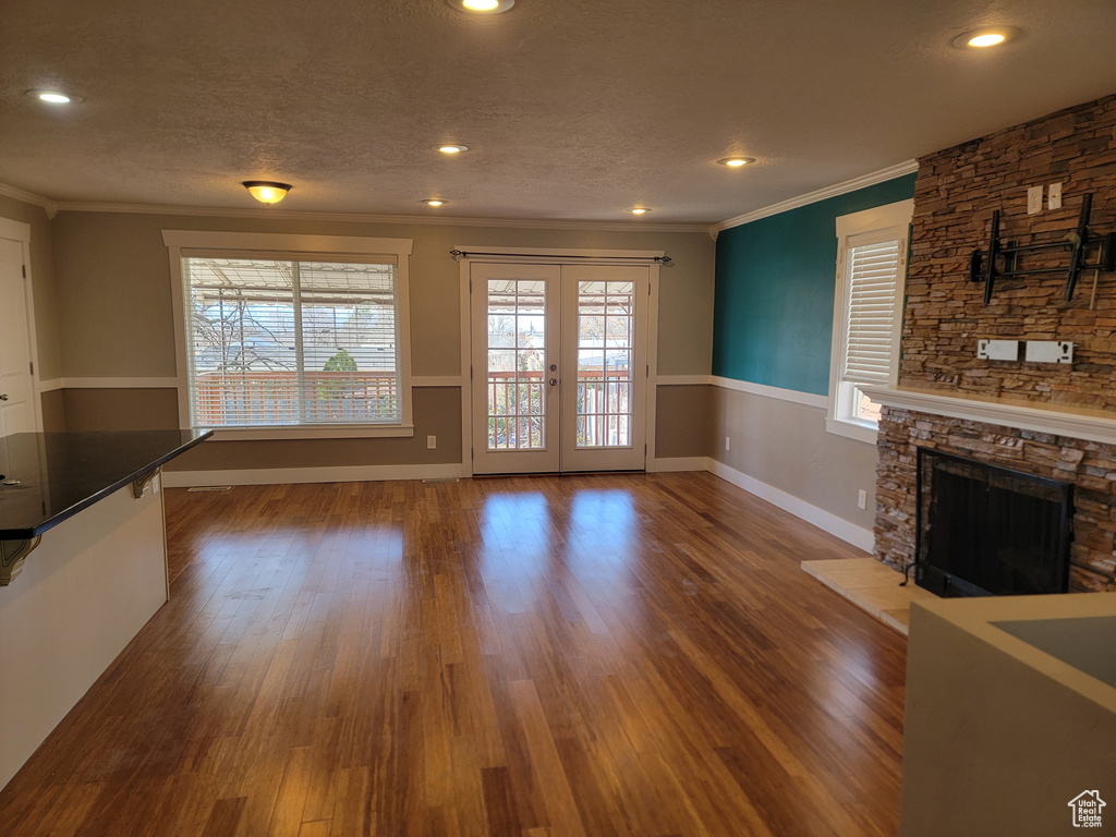 Unfurnished living room featuring ornamental molding, recessed lighting, a fireplace, wood finished floors, and baseboards