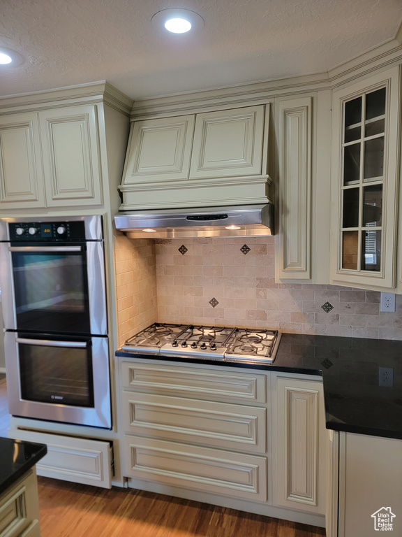 Kitchen featuring appliances with stainless steel finishes, cream cabinets, dark countertops, a textured ceiling, and recessed lighting