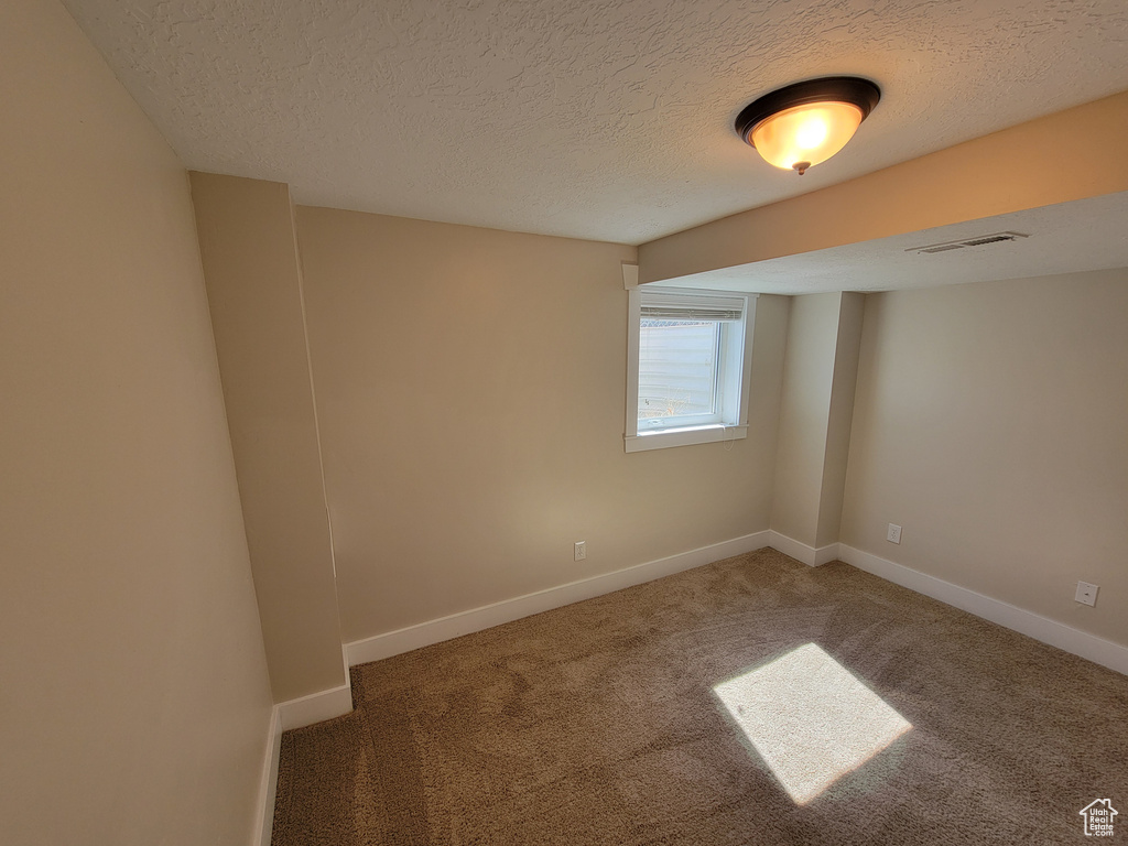 Unfurnished room with carpet flooring, a textured ceiling, and baseboards