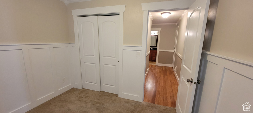 Corridor with ornamental molding, a wainscoted wall, and a decorative wall