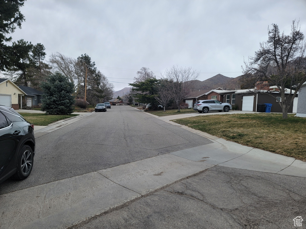 View of asphalt road with a residential view and curbs