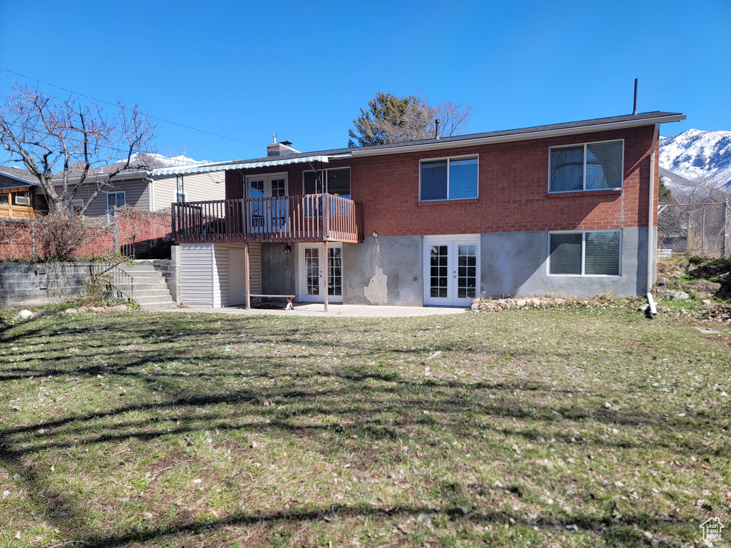Back of house with french doors, stairs, a yard, a deck with mountain view, and a patio