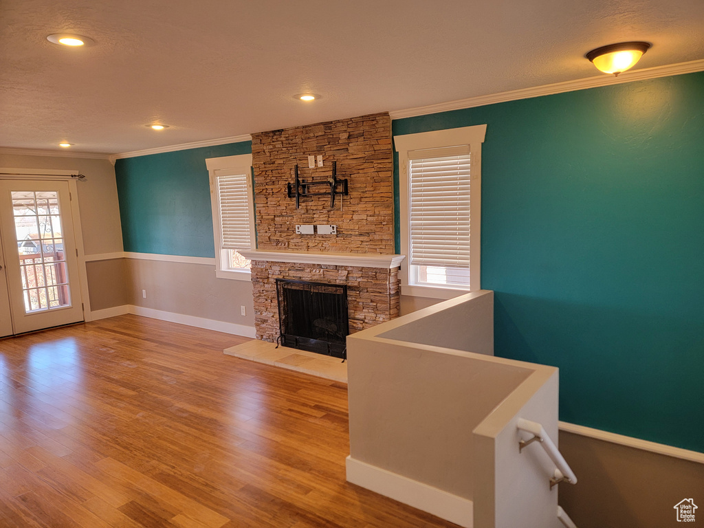 Unfurnished living room with ornamental molding, a fireplace, wood finished floors, baseboards, and recessed lighting