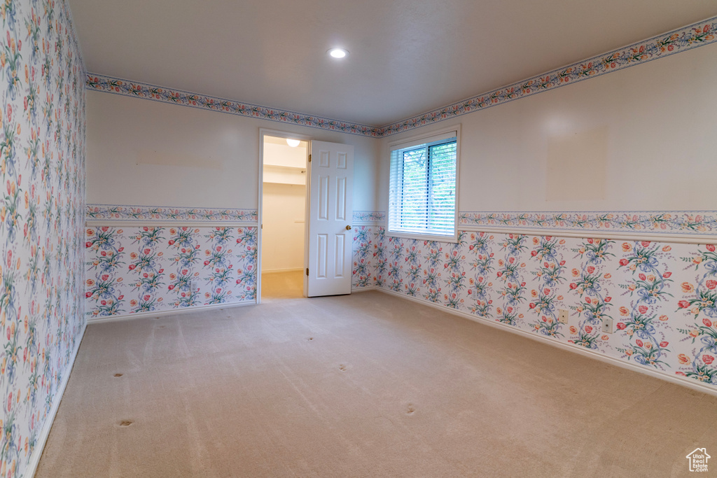 Carpeted empty room featuring wallpapered walls, recessed lighting, baseboards, and a wainscoted wall