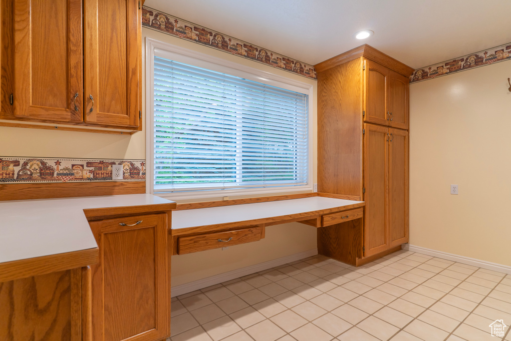 Kitchen with light countertops, brown cabinets, light tile patterned floors, baseboards, and recessed lighting