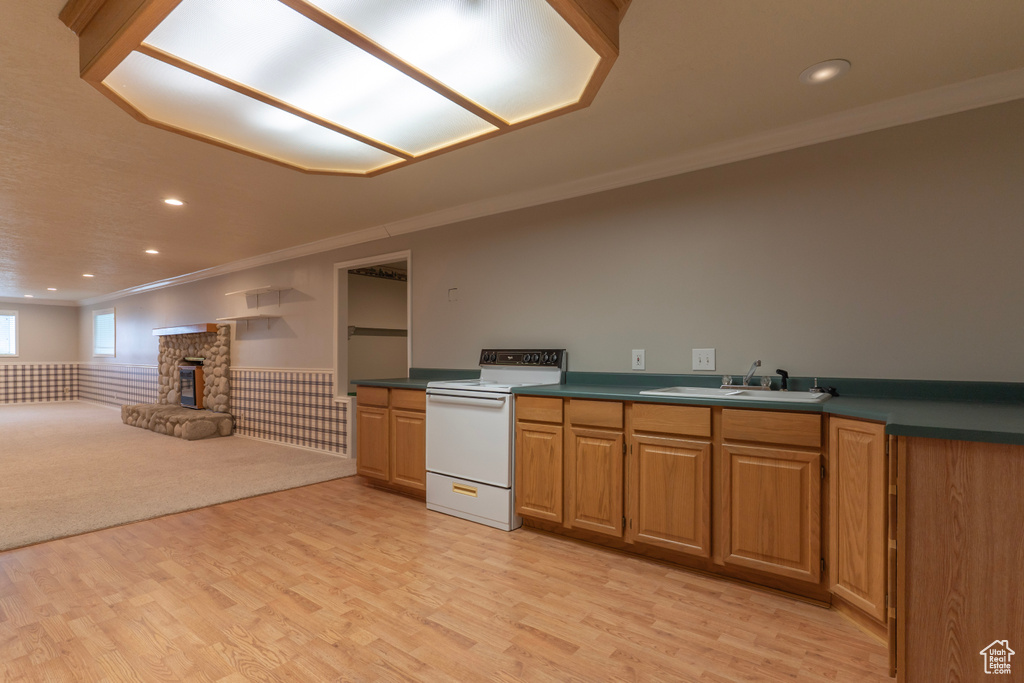 Kitchen with electric range, a sink, crown molding, a fireplace, and wainscoting