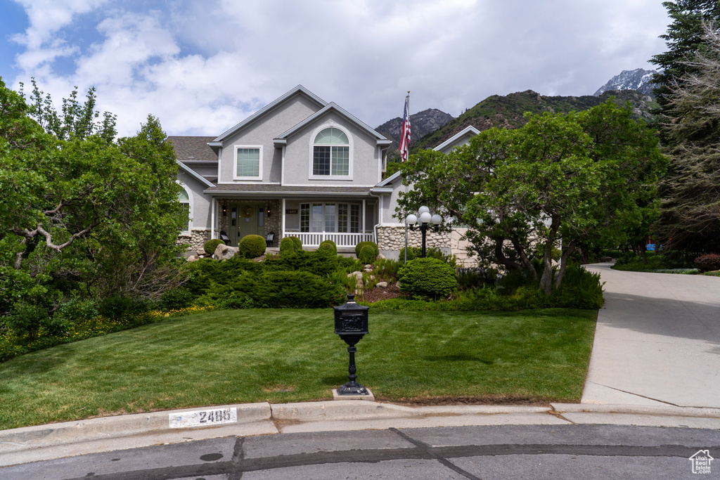 Traditional home with a front yard, covered porch, stone siding, and stucco siding